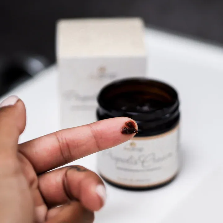 Creme auf Finger mit Cremebehälter im Hintergrund